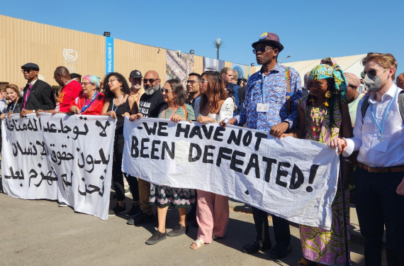 Left banner: There is no climate justice without human rights. We are not defeated yet. Right banner: We have not been defeated!