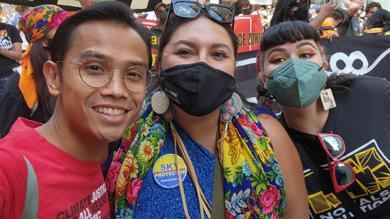A small group of GGJ staff and members in colorful clothing smile at the camera, some wearing face masks.