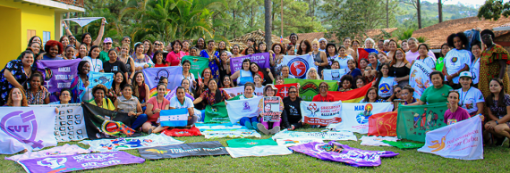 Around 100 IFOS participants gather for a group shot with many organizational banners.