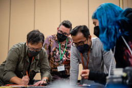 Group of people with masks engaged in a focused activity at a table